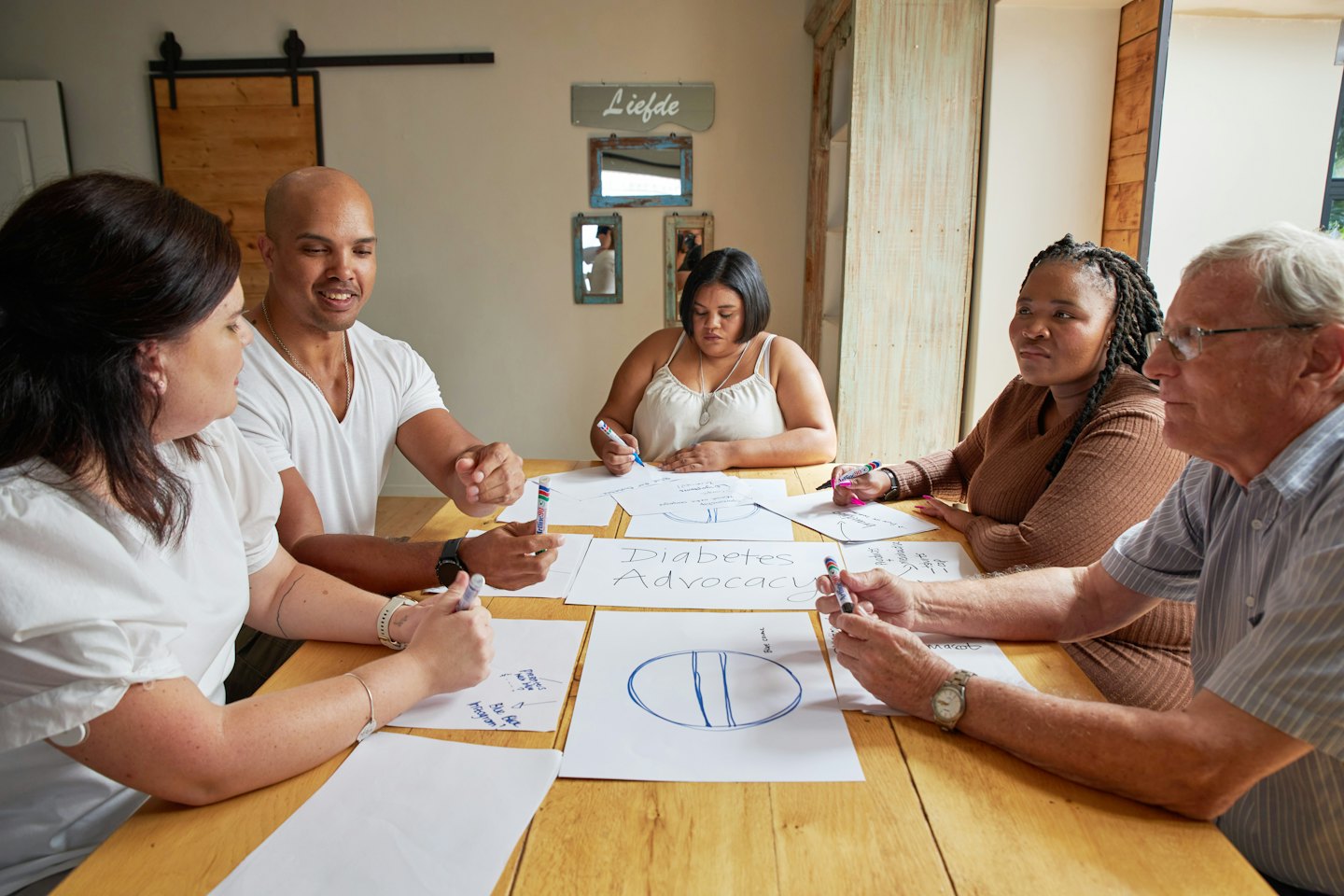 Adulti diversi collaborano attorno a un tavolo con documenti su 'Advocacy per il Diabete'.