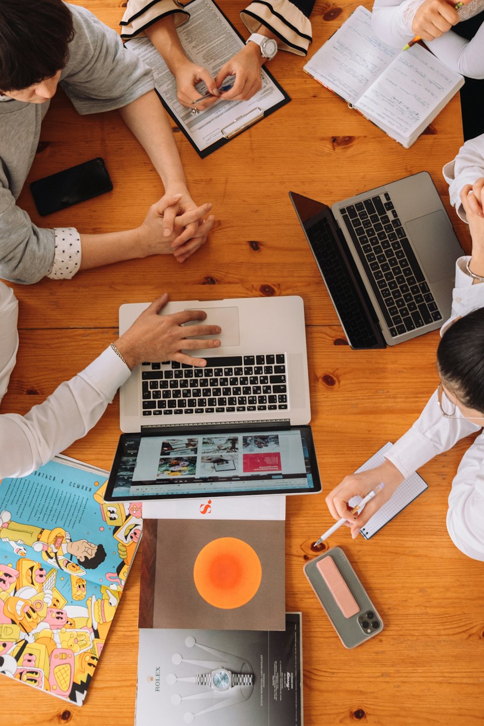 Professionisti che collaborano attorno a un tavolo con laptop e documenti.